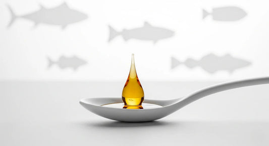 Spoon with a drop of oil on a white background with fish illustrations.