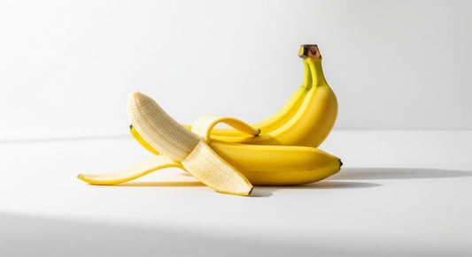 Two bananas, one peeled, on a white background